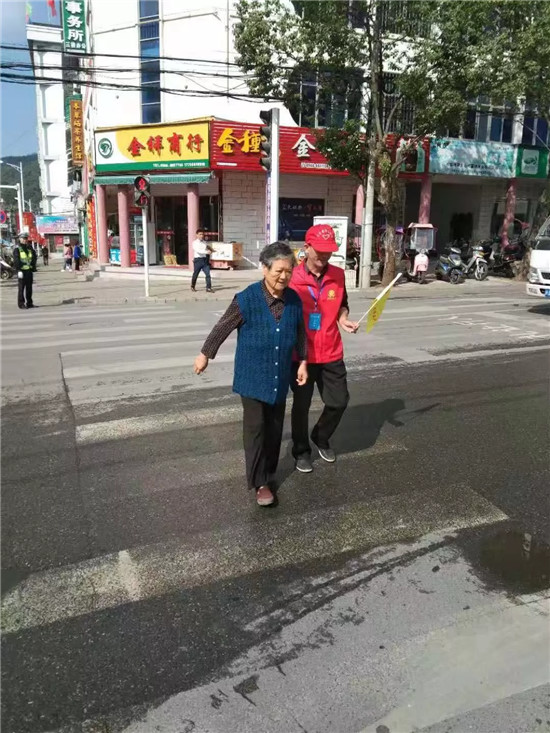遇到行动不便的老人要过马路时,志愿者主动上前搀扶